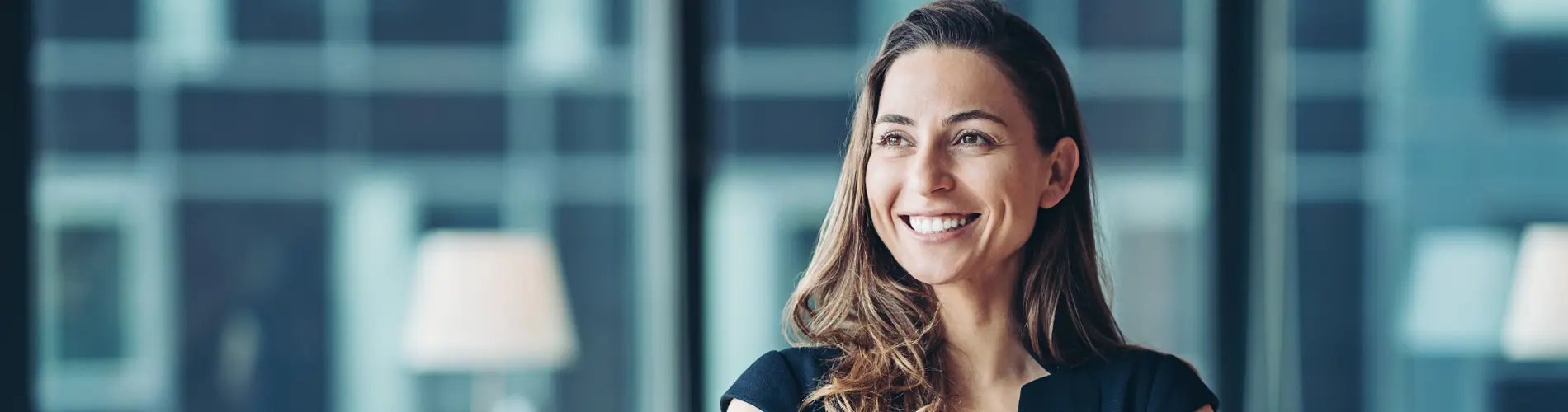 Femme avec les bras croisés, dans les bureaux d'Amundi, symbole de l'expertise en gestion d'actifs.