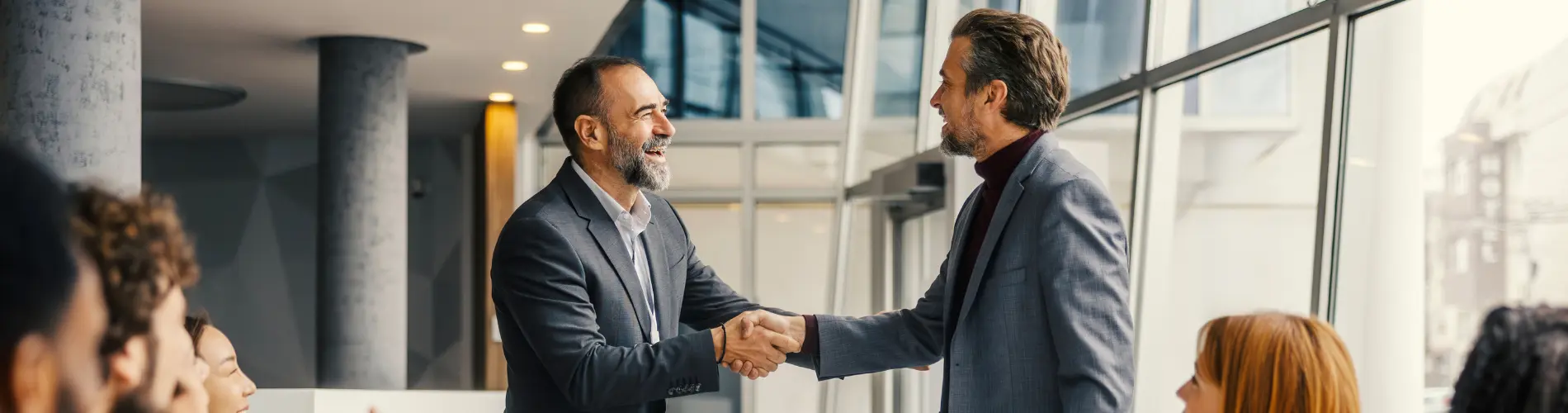 Deux professionnels se serrent la main dans les bureaux d'Amundi, applaudis par des collègues.