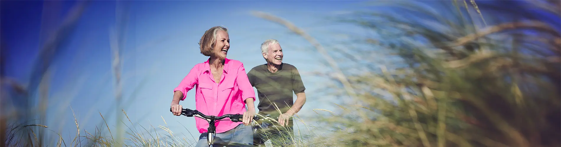 Couple senior heureux se promenant à vélo, arrière-plan de nature et ciel bleu.