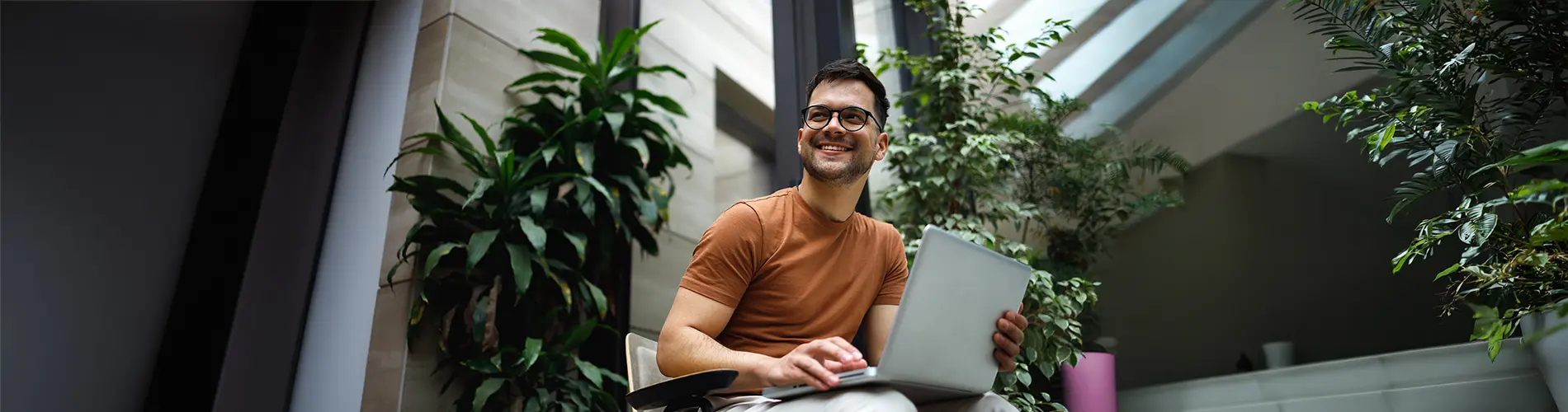 Un gestionnaire d'actifs souriant travaille sur un ordinateur portable dans les bureaux d'Amundi.
