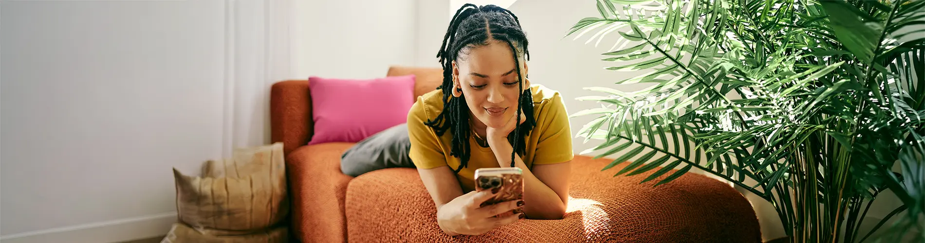 Femme concentrée sur son téléphone dans un cadre décontracté, symbolisant la gestion financière.