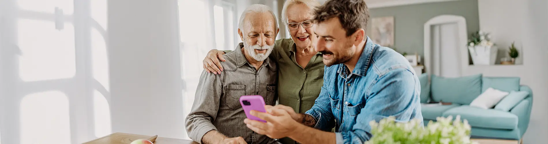 Un gestionnaire d'actifs montre des informations financières sur son téléphone à deux personnes âgées.