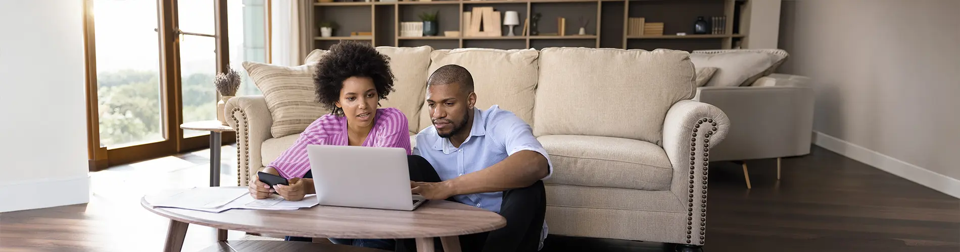 Un couple examine des investissements sur un ordinateur portable dans un cadre confortable.