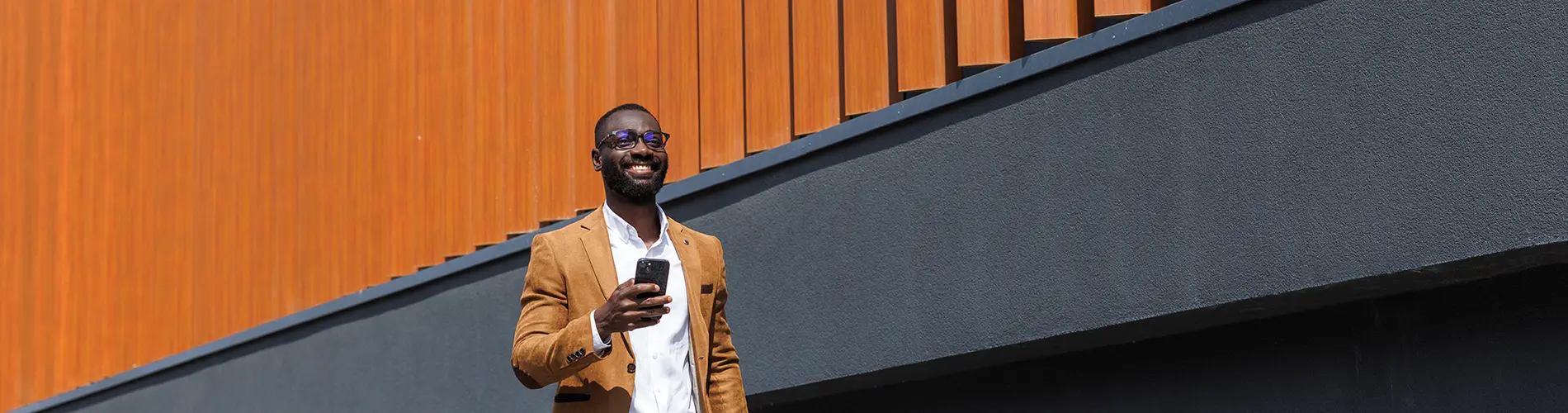 Un gestionnaire d'actifs souriant marchant dans un milieu urbain moderne.