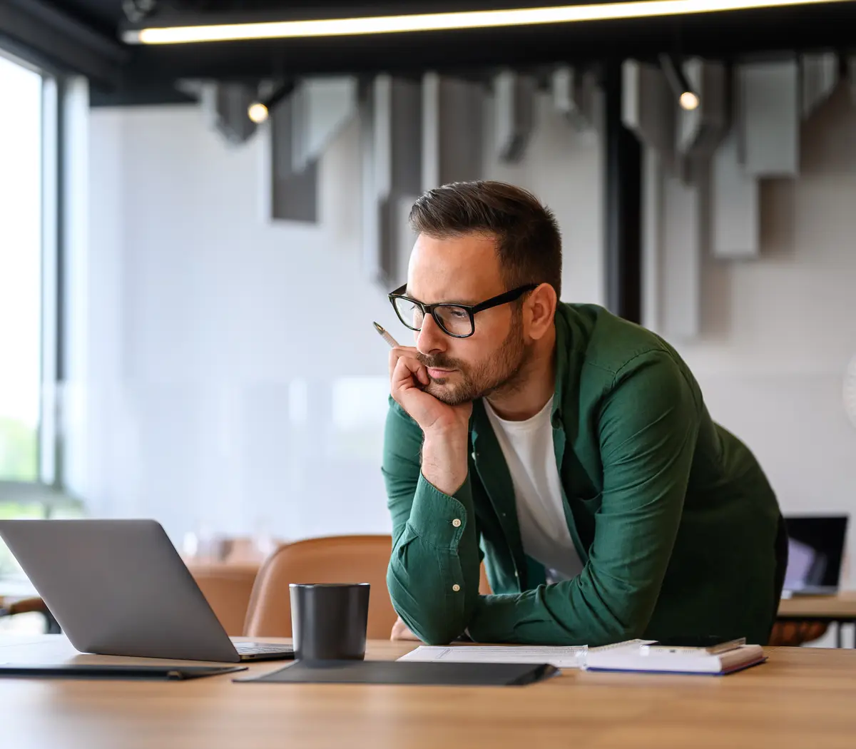 Un expert financier se penche sur son bureau, dans les bureaux d'Amundi, réfléchissant à des stratégies d'investissement.