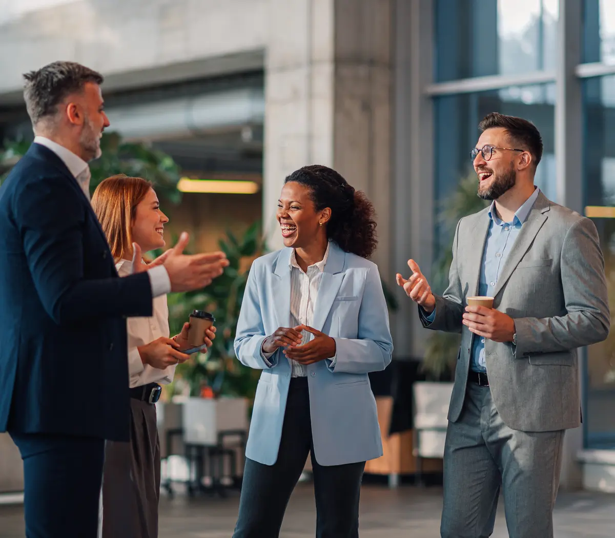 Quatre experts financiers discutent joyeusement dans leurs bureaux.