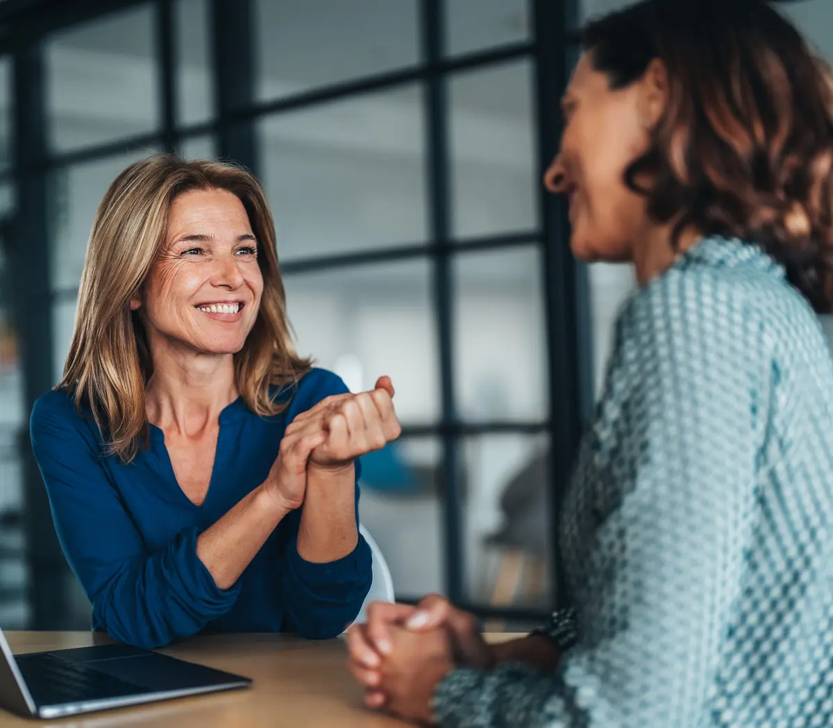 Deux femmes discutent dans les bureaux de leur entreprise, l'une est responsable des ressources humaines.