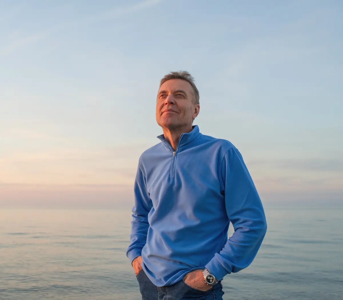 Homme souriant en bord de mer, représentant un futur retraité.