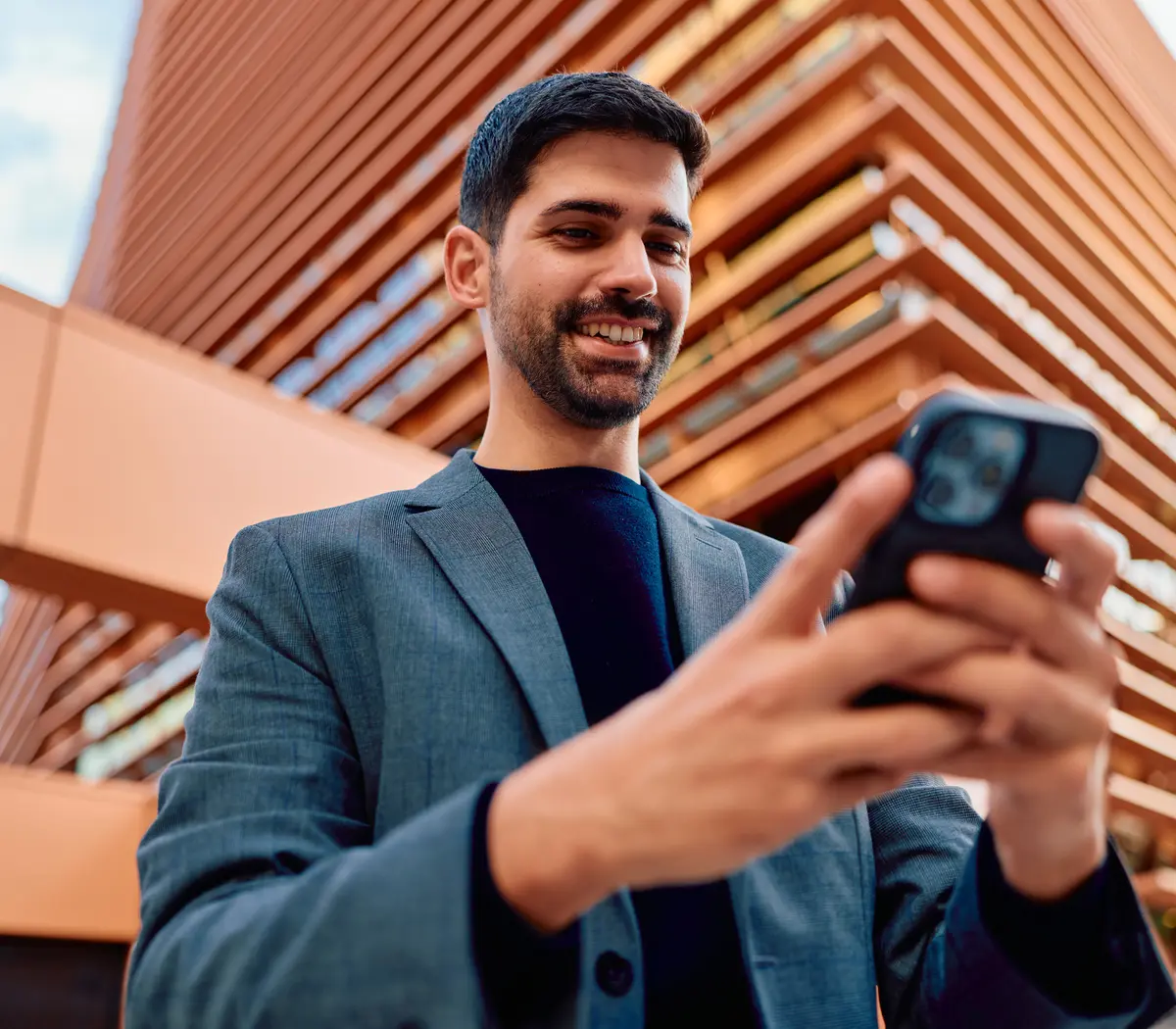 Un salarié consulte son téléphone devant un bâtiment moderne .