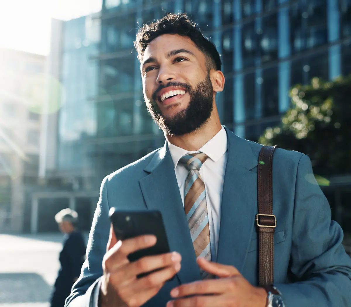 Un gestionnaire financier en costume vérifiant son téléphone dans un environnement urbain.