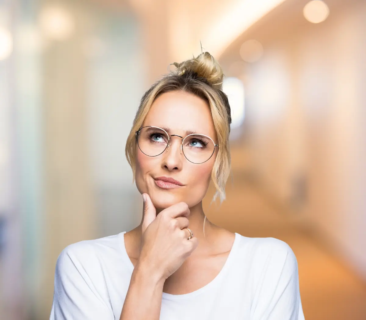Une salarié réfléchit, yeux levés vers le ciel.