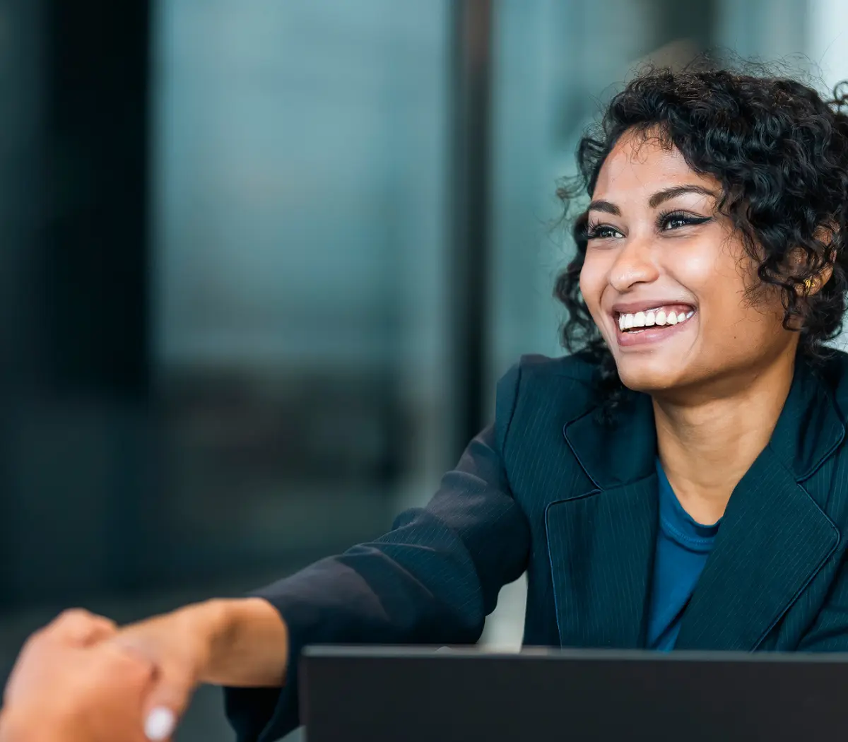 Professionnelle souriante serrant la main dans les bureaux d'Amundi, contexte de gestion d'actifs.