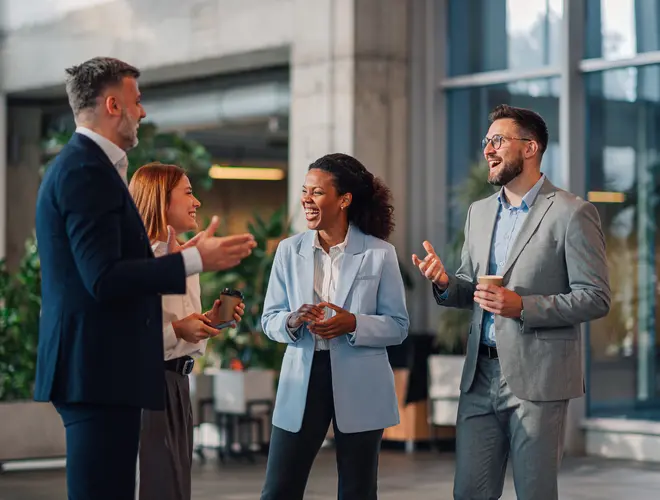 Quatre experts financiers discutent joyeusement dans leurs bureaux.