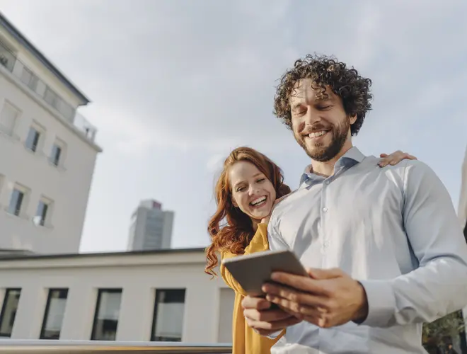 Couple qui sort d'une visite d'appartement et qui regarde la situation de son épargne salariale.