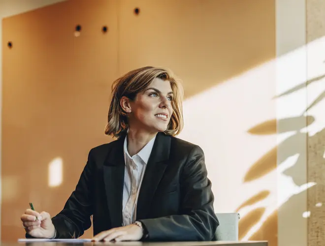 Un gestionnaire d'actifs réfléchissant dans les bureaux d'Amundi, lumière douce à l'arrière-plan.