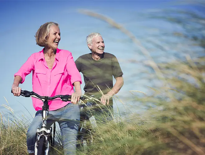 Couple senior heureux se promenant à vélo, arrière-plan de nature et ciel bleu.