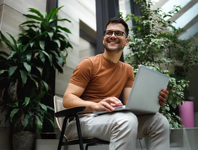 Un gestionnaire d'actifs souriant travaille sur un ordinateur portable dans les bureaux d'Amundi.