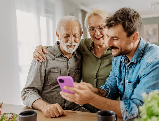 Un gestionnaire d'actifs montre des informations financières sur son téléphone à deux personnes âgées.