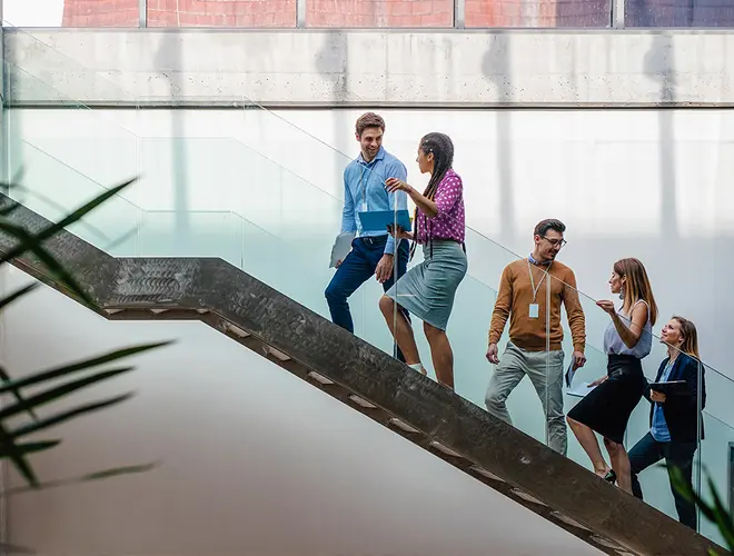 Groupe de personnes descendant un escalier dans les bureaux d'Amundi, ambiance dynamique.