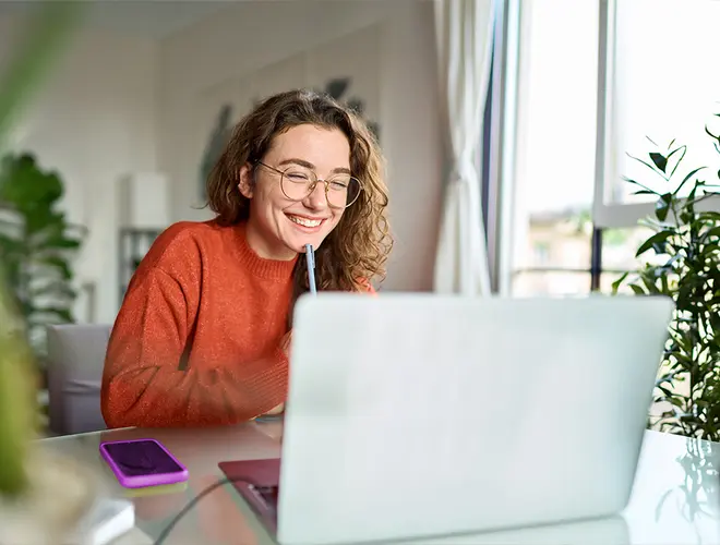 Une experte en gestion d'actifs souriante travaille sur son ordinateur dans les bureaux d'Amundi.