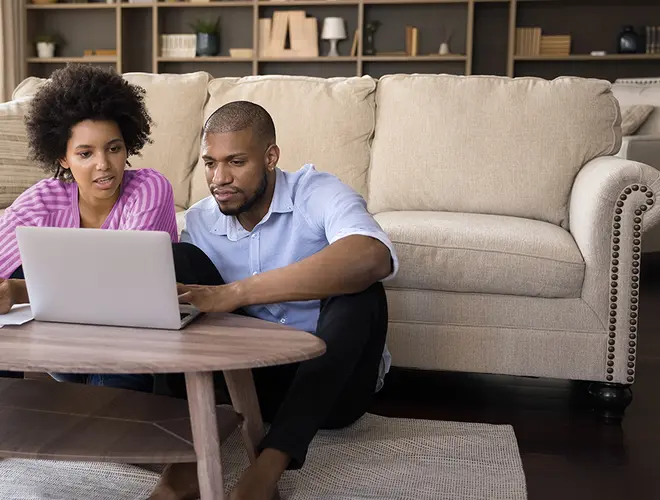 Un couple examine des investissements sur un ordinateur portable dans un cadre confortable.