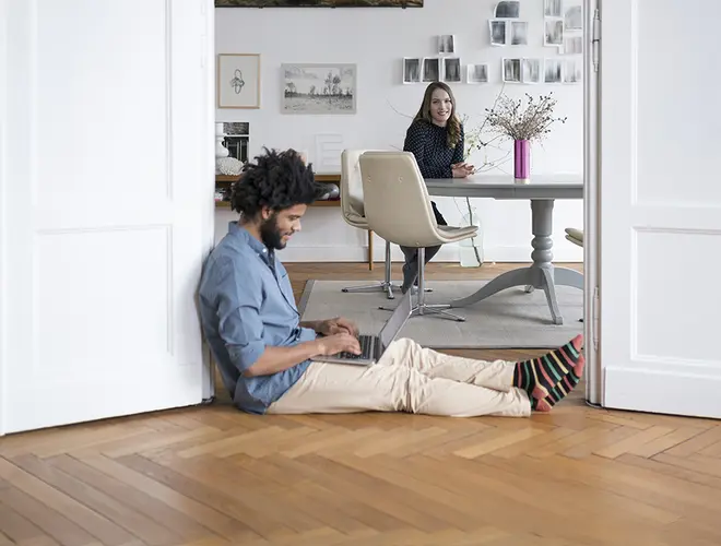 Un expert financier assis sur le sol, travaillant avec une tablette, dans les bureaux d'Amundi.