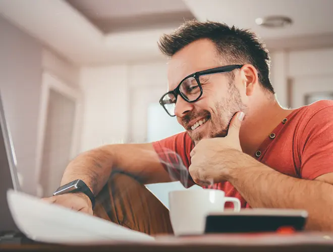 Un gestionnaire d'actifs souriant travaillant sur un ordinateur dans un bureau moderne.