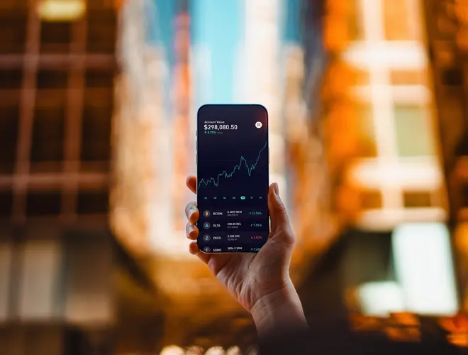 Un expert en finance tient un smartphone affichant une courbe de croissance financière.