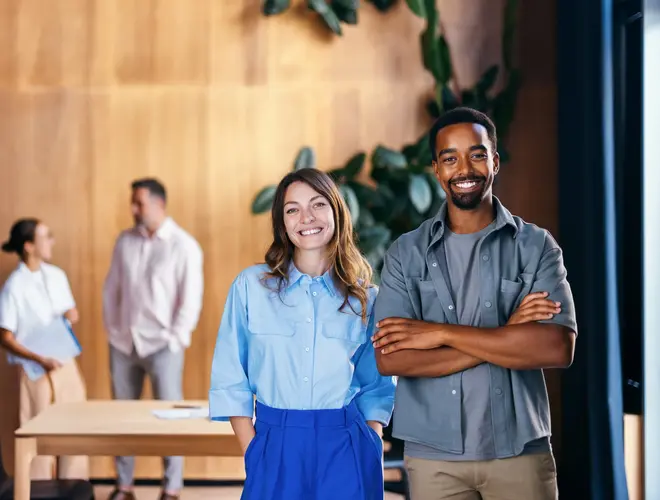 Deux jeunes salariés souriants dans des bureaux.