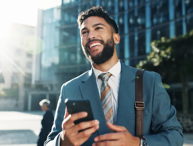Un gestionnaire financier en costume vérifiant son téléphone dans un environnement urbain.