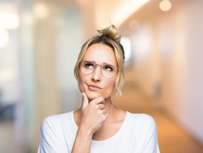 Une salarié réfléchit, yeux levés vers le ciel.