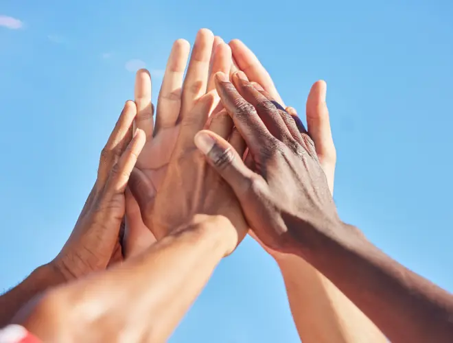 Mains de plusieurs personnes se rejoignant sous un ciel bleu, symbolisant la collaboration en finance.