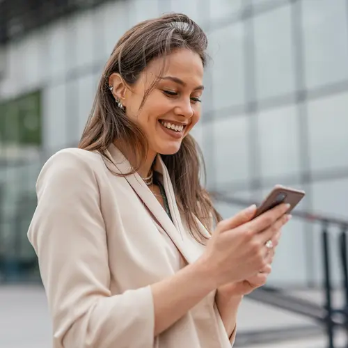 Professionnelle consultant son téléphone devant un bâtiment.