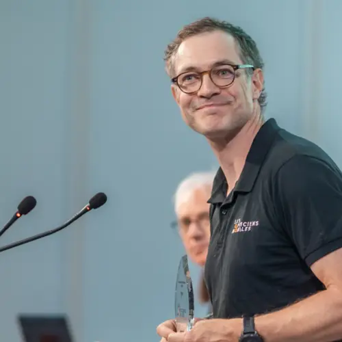 Un expert en finance souriant, tenant un prix, dans les bureaux d'Amundi.