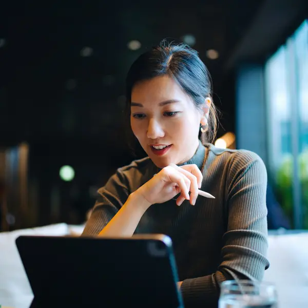 Professionnelle de la finance dans les bureaux d'Amundi, utilisant une tablette et réfléchissant.