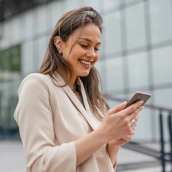 Professionnelle consultant son téléphone devant un bâtiment.