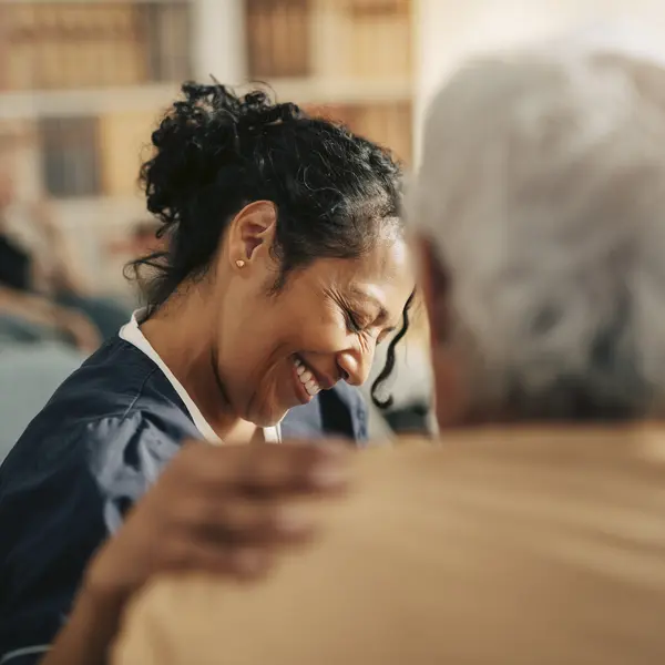 Une femme souriante touche l'épaule d'une personne agée.