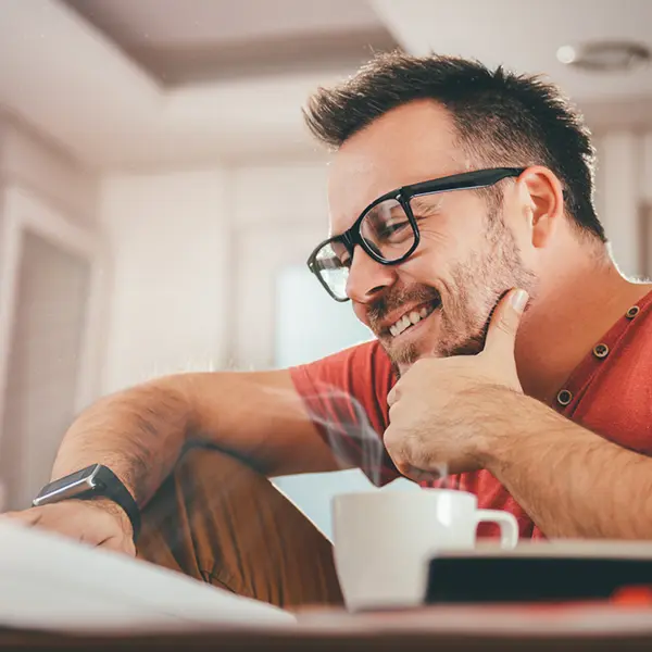 Un gestionnaire d'actifs souriant travaillant sur un ordinateur dans un bureau moderne.