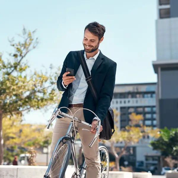 Un gestionnaire d'actifs souriant consulte son téléphone à côté de son vélo en milieu urbain.