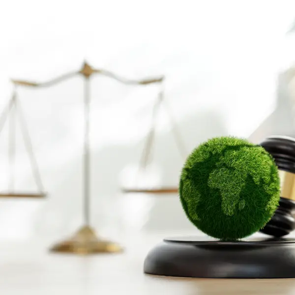 Un globe vert sur un maillet de juge, symbole d'une gestion financière durable. Balance en arrière-plan.