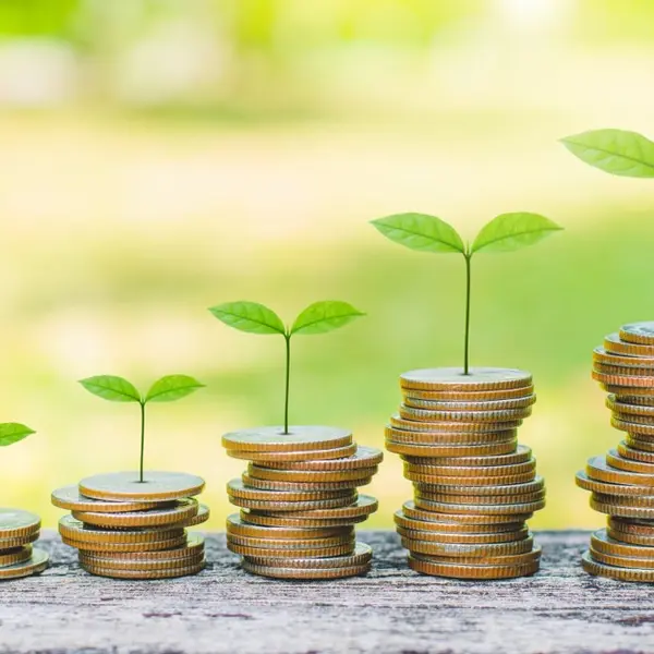 Des pièces de monnaie empilées avec des pousses vertes symbolisant la croissance financière.
