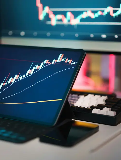 Graphiques de marché financier affichés sur un ordinateur et une tablette dans les bureaux d'Amundi.