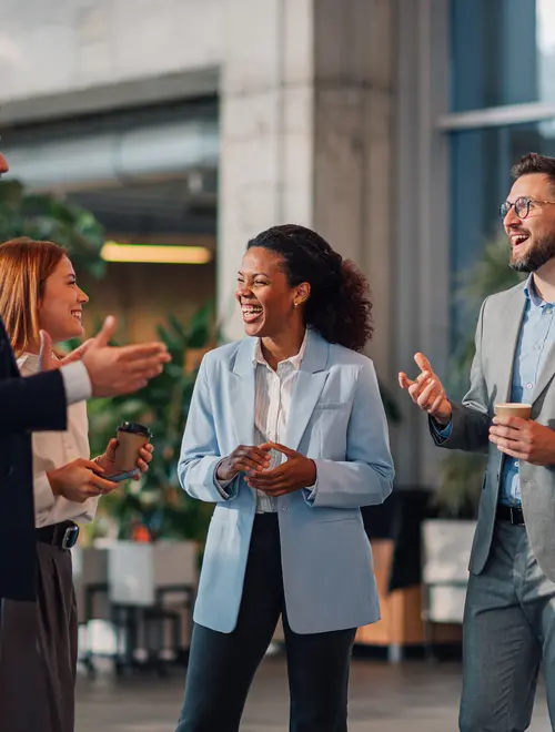 Quatre experts financiers discutent joyeusement dans leurs bureaux.