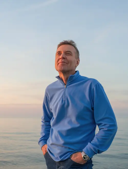 Homme souriant en bord de mer, représentant un futur retraité.