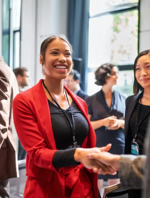 Femme souriante en blazer qui sert la main à une autre femme.