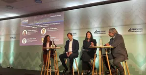 Panel discussion at the PRI in-person event in Amsterdam, with four speakers seated on stools on an Amundi-branded stage. A presentation screen shows “A New Blueprint for Financing the Green Transition in Emerging Markets” and the Global Green Bond Initiative.