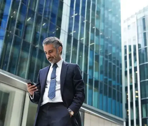 uomo che guarda il cellulare con sfondo palazzi di vetro