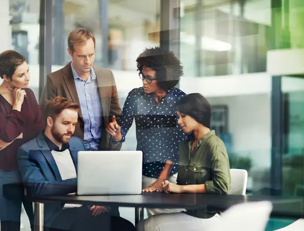 Gruppe diskutiert im Büro vor Laptop