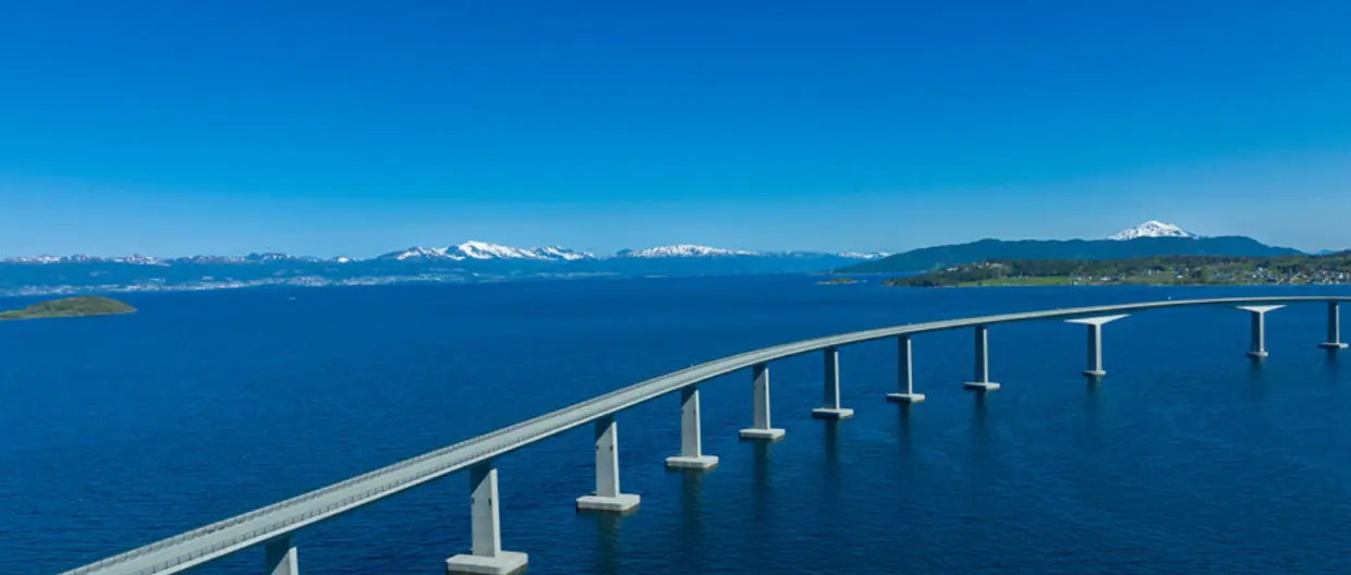 immagine con ponte su mare con montagne