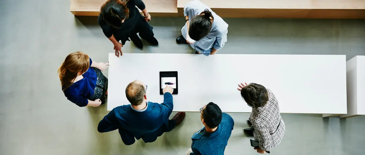 vista dall'alto di un gruppo di impiegati intorno ad un tavolo che consultano un tablet